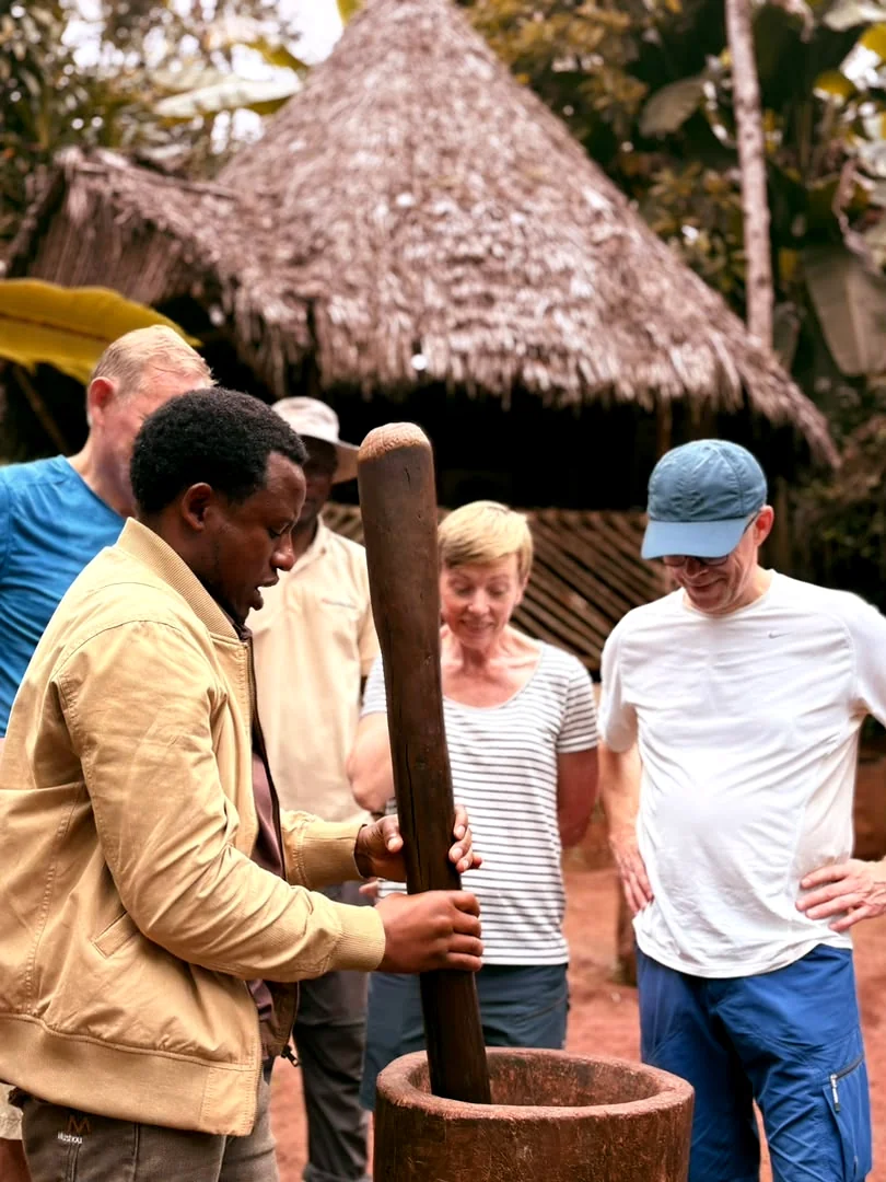Justin working the wooden mortar while guests stand close around him