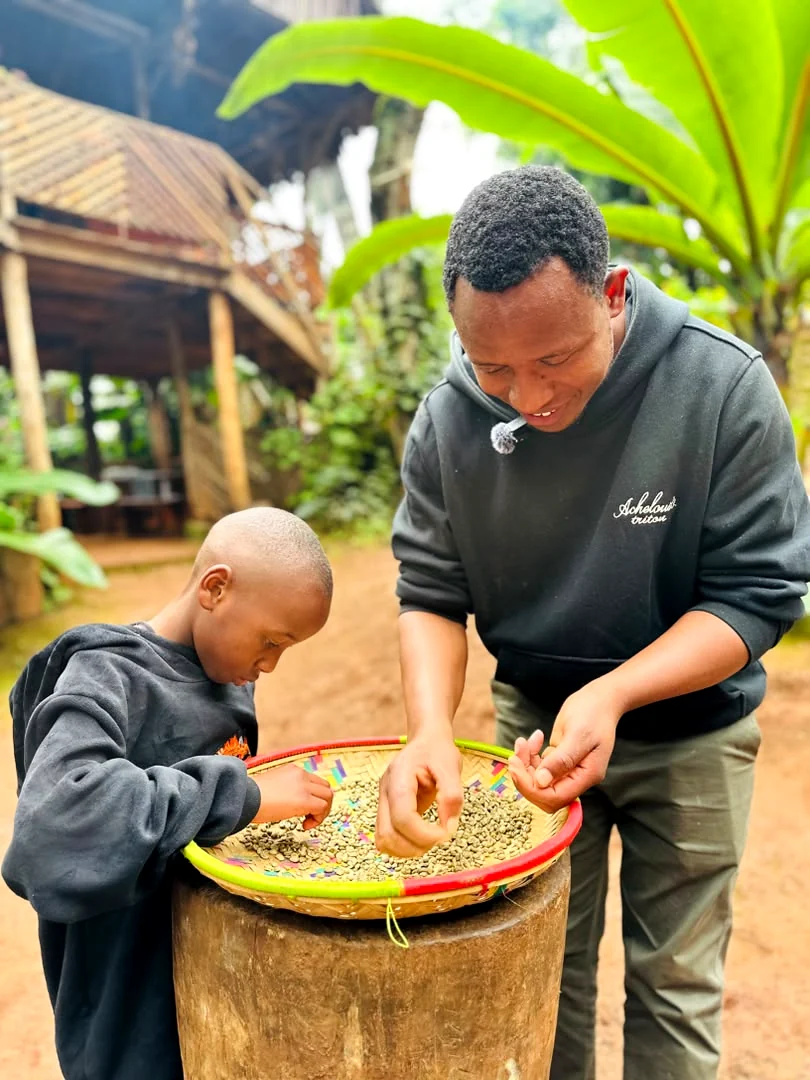 Justin and his young son bending over a woven basket of green coffee beans, sorting them together